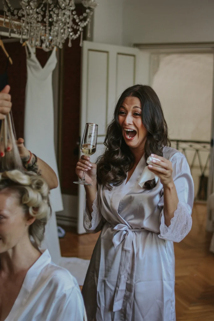 Préparatifs de mariage capturés par un photographe mariage authentique : une invitée trinque avec émotion avant la cérémonie.