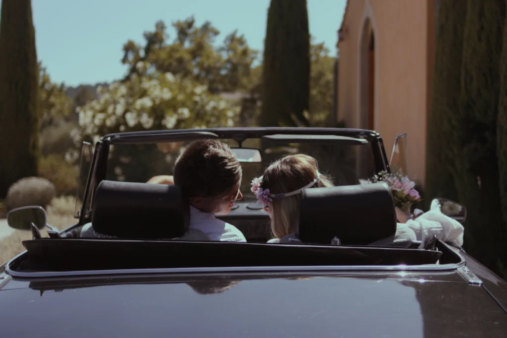 Mariée et marié s'enlaçant tendrement dans leur voiture décapotable après la cérémonie.