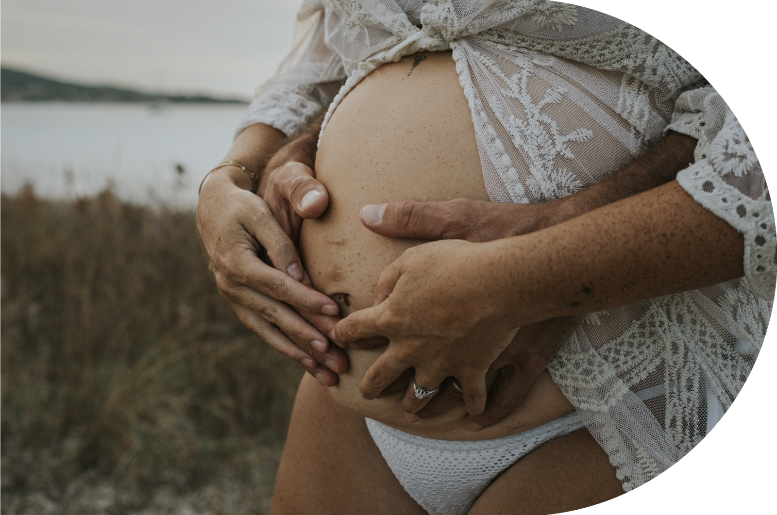 Un couple, posant tendrement leurs mains sur le ventre rond de la futur maman.