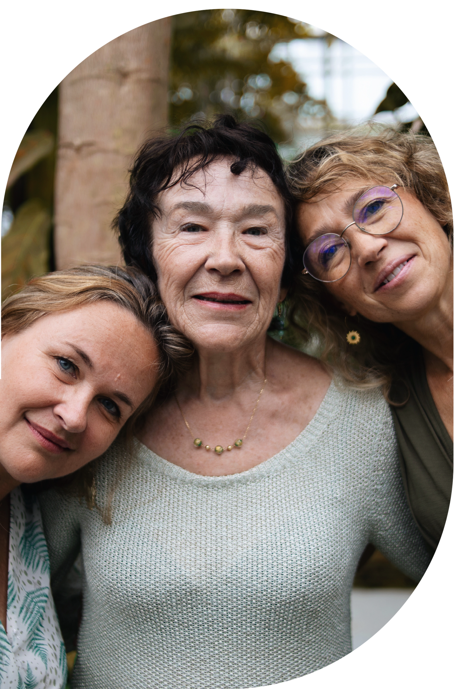 Une mère et ses deux filles, dans un espace végétalisé d'Aix-en-Provence, partagent un moment tendre lors d'une séance photo.