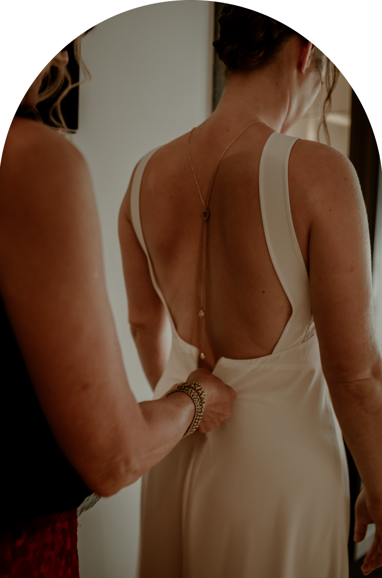 Un mère, fermant délicatement la robe de mariée en satin de sa fille. Une photo des préparatifs d'un mariage dans le Luberon.