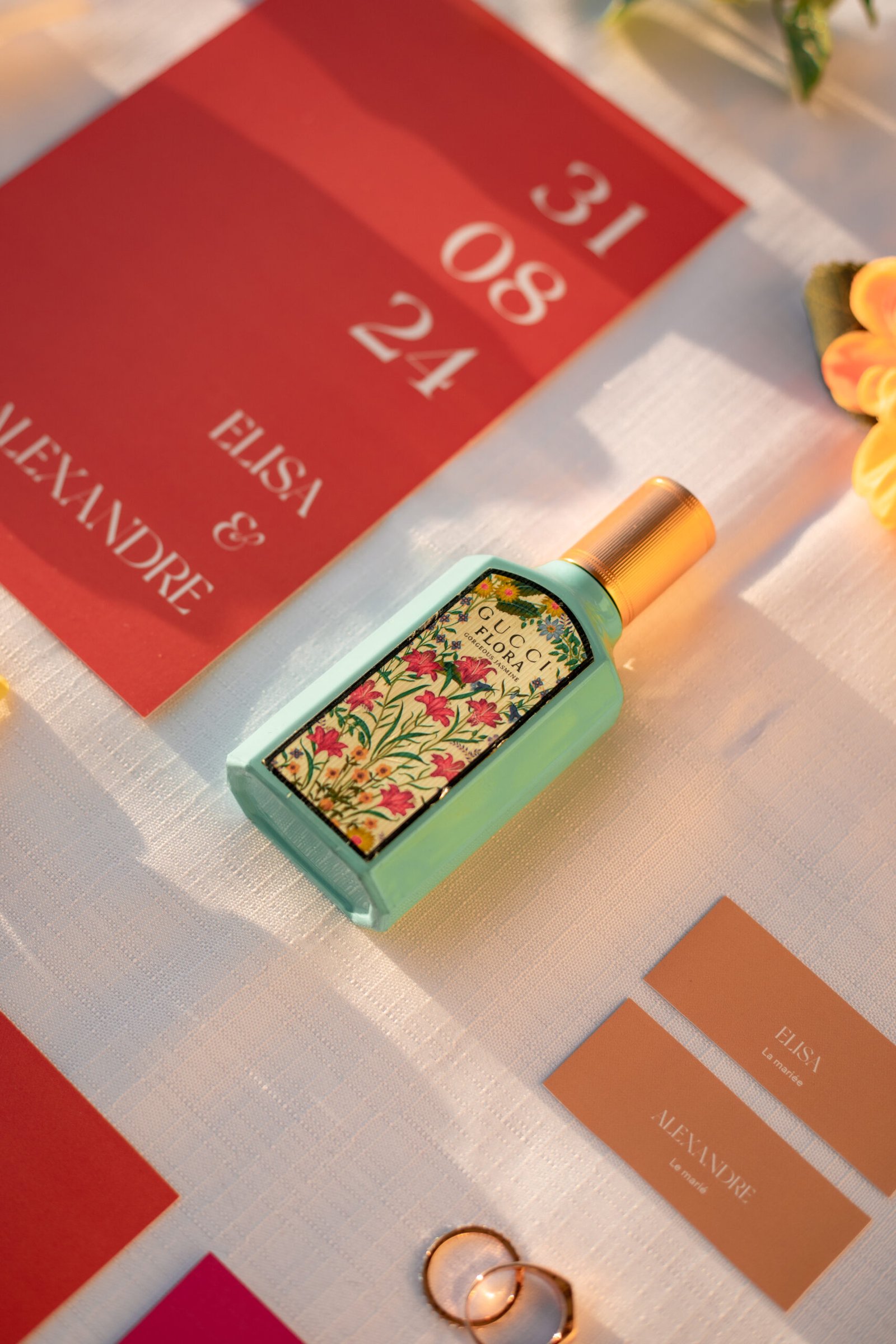 Un parfum de la marque Gucci Flora coloré est entouré de différents éléments pour créer un flatlay de mariage coloré.