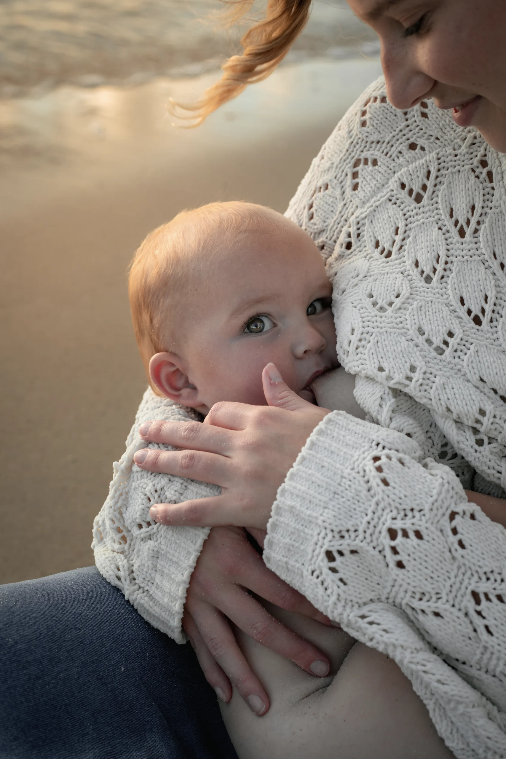 Un bébé, dans les bras de sa mère, nu, tétant le sein pour un service de photo de maternité. Photographe mariage Provence et séance photo maman et bébé.