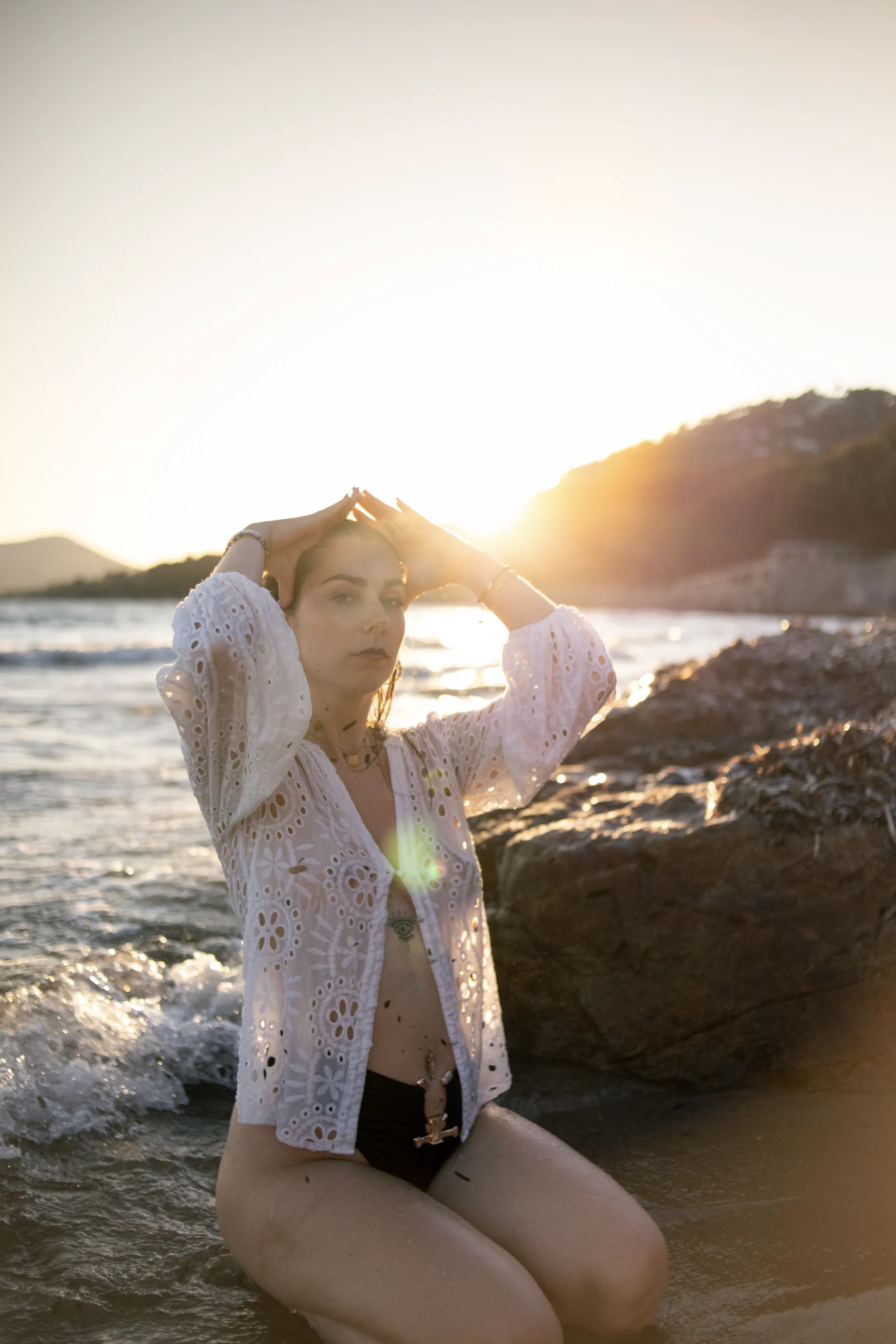 Une femme, agenouillée au bord de l'eau, avec un air confiant, regardant l'objectif. Elle se sent à l'aise grâce à la bonne relation client photographe qui s'est construite.