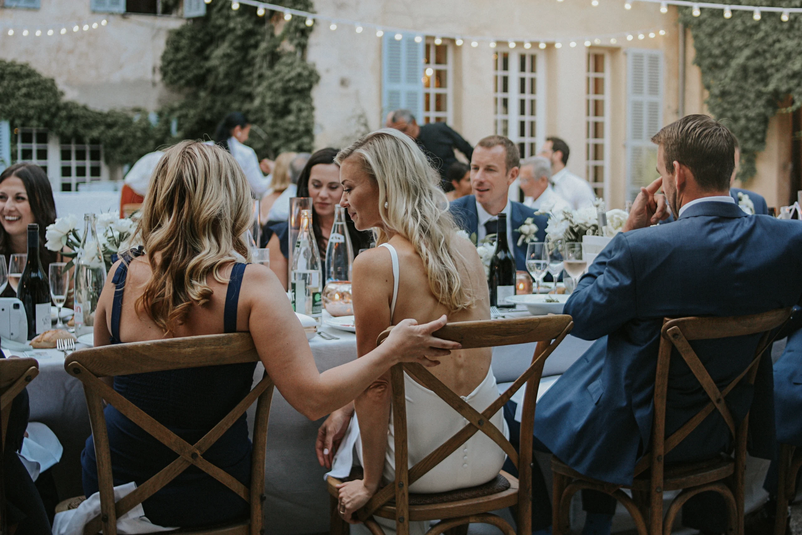 Une mariée, attablée aux cotés de son époux et de sa demoiselle d'honneur, ne prêtant pas attention à l'objectif. Elle a confiance en son prestataire, car ils ont mis en place une vraie relation client photographe.