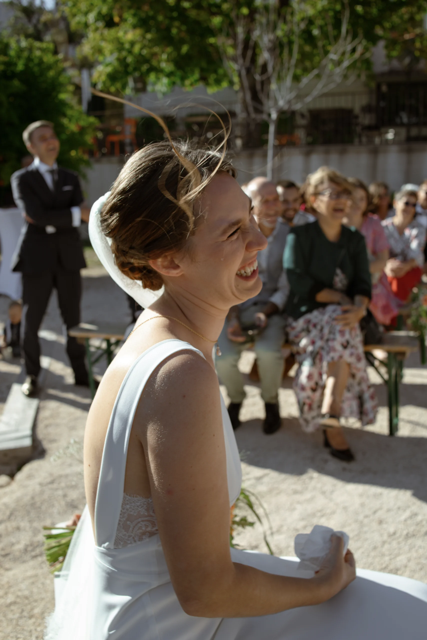 Une mariée, regardant avec amour et émotion son mari pendant leur cérémonie laique en Provence. Une larme coule sur son visage, car elle se sent pleinement à l'aise avec son prestataire photo grâce à une bonne relation client photographe.