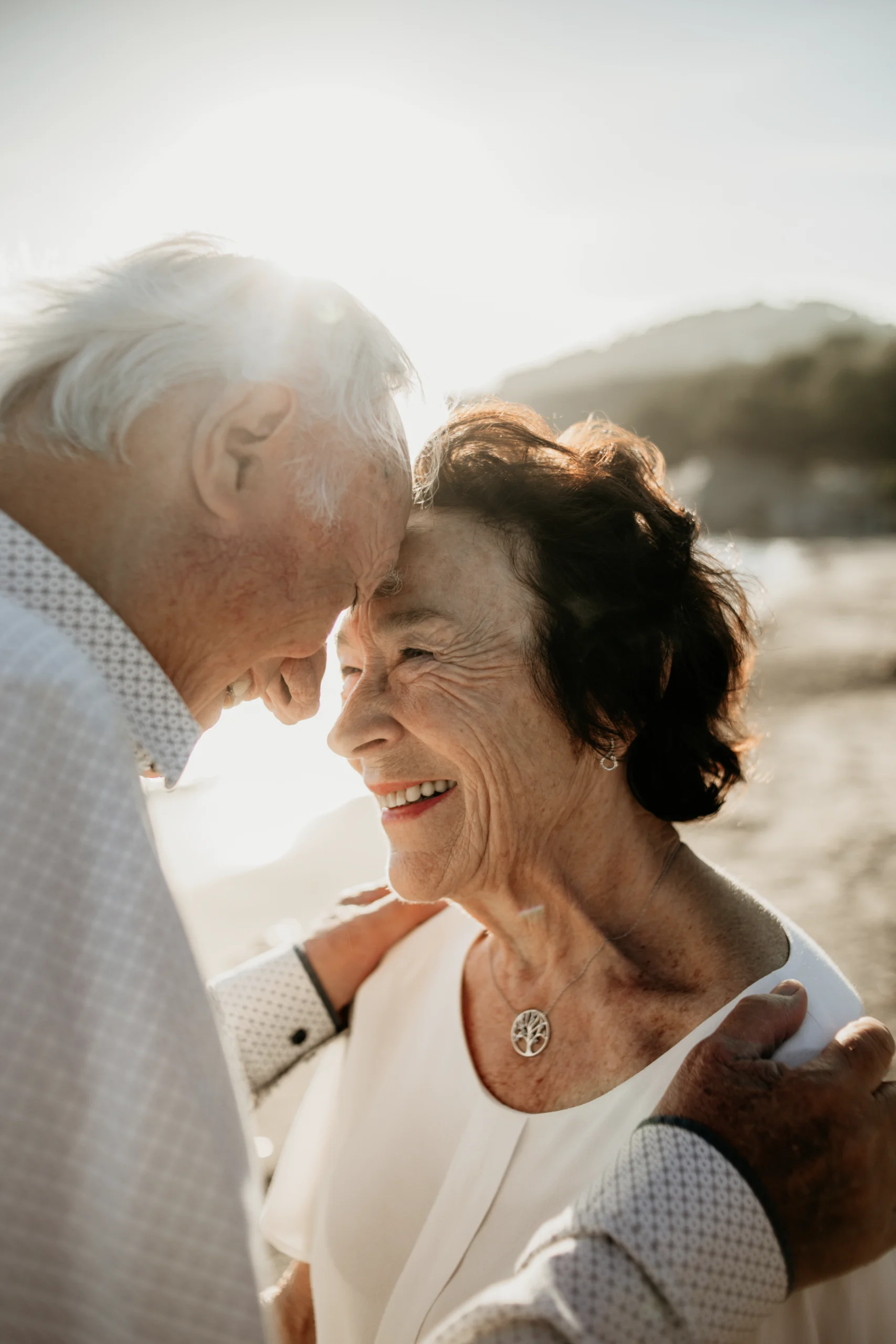 Un couple âgé, riant au éclats, front contre front, sur une plage aux alentours de St Tropez.
