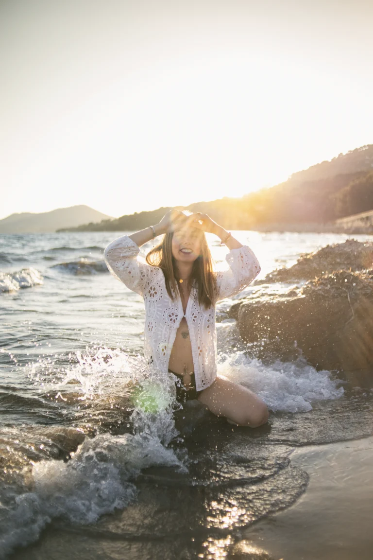 Jeune femme, agenouillée au bord de l'eau. Un moment de confiance en soi immortalisée lors d'une séance photo portrait à Hyères.