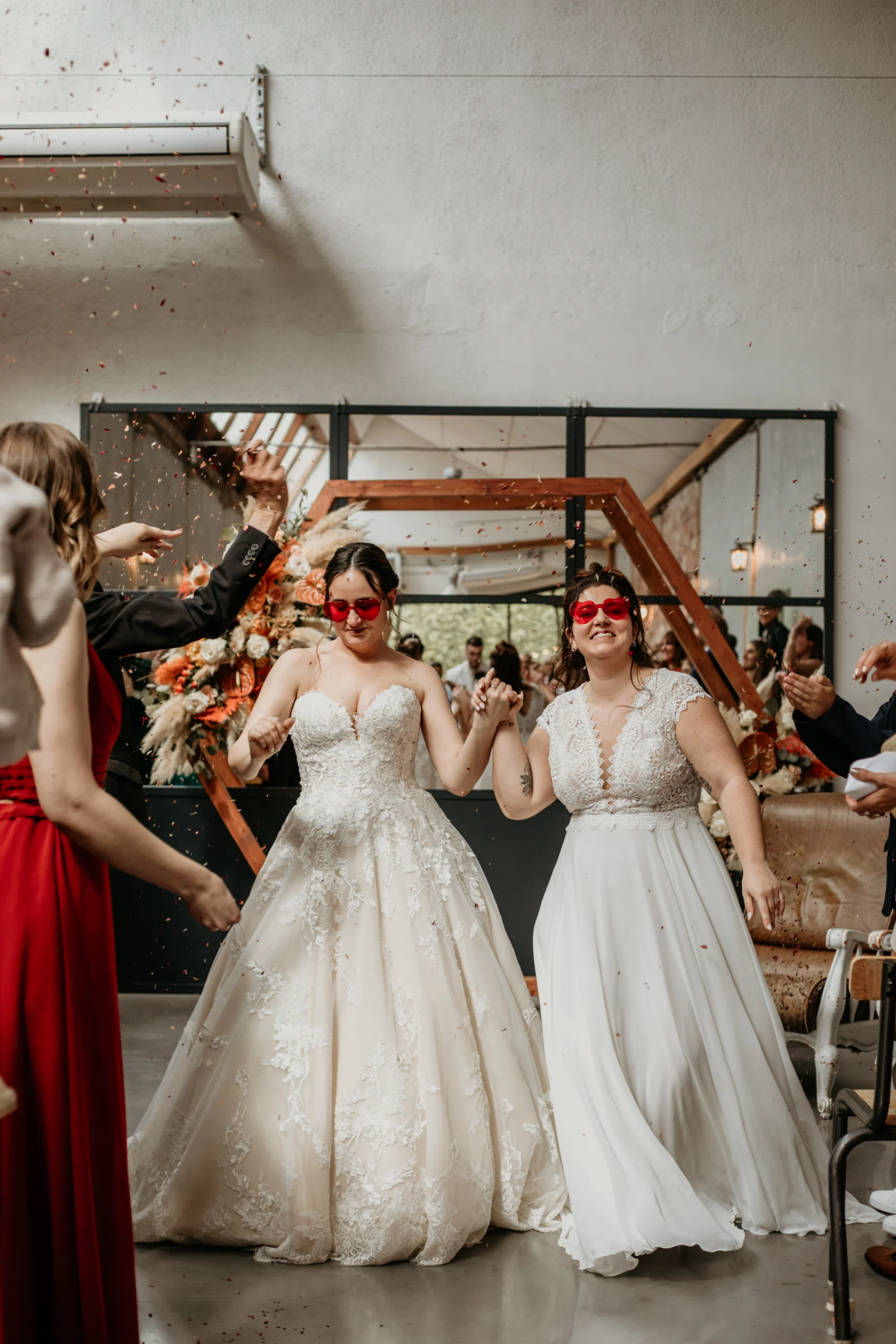 Une couple de jeunes mariées, se tenant la main et dansant pour quitter leur cérémonie de mariage laique.