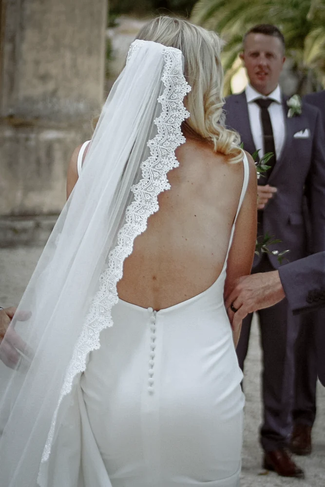 Photographie naturelle d'un mariage en Provence, montrant une mariée de dos, vêtue d'une robe dos nu et d'un voile ornée de dentelles.