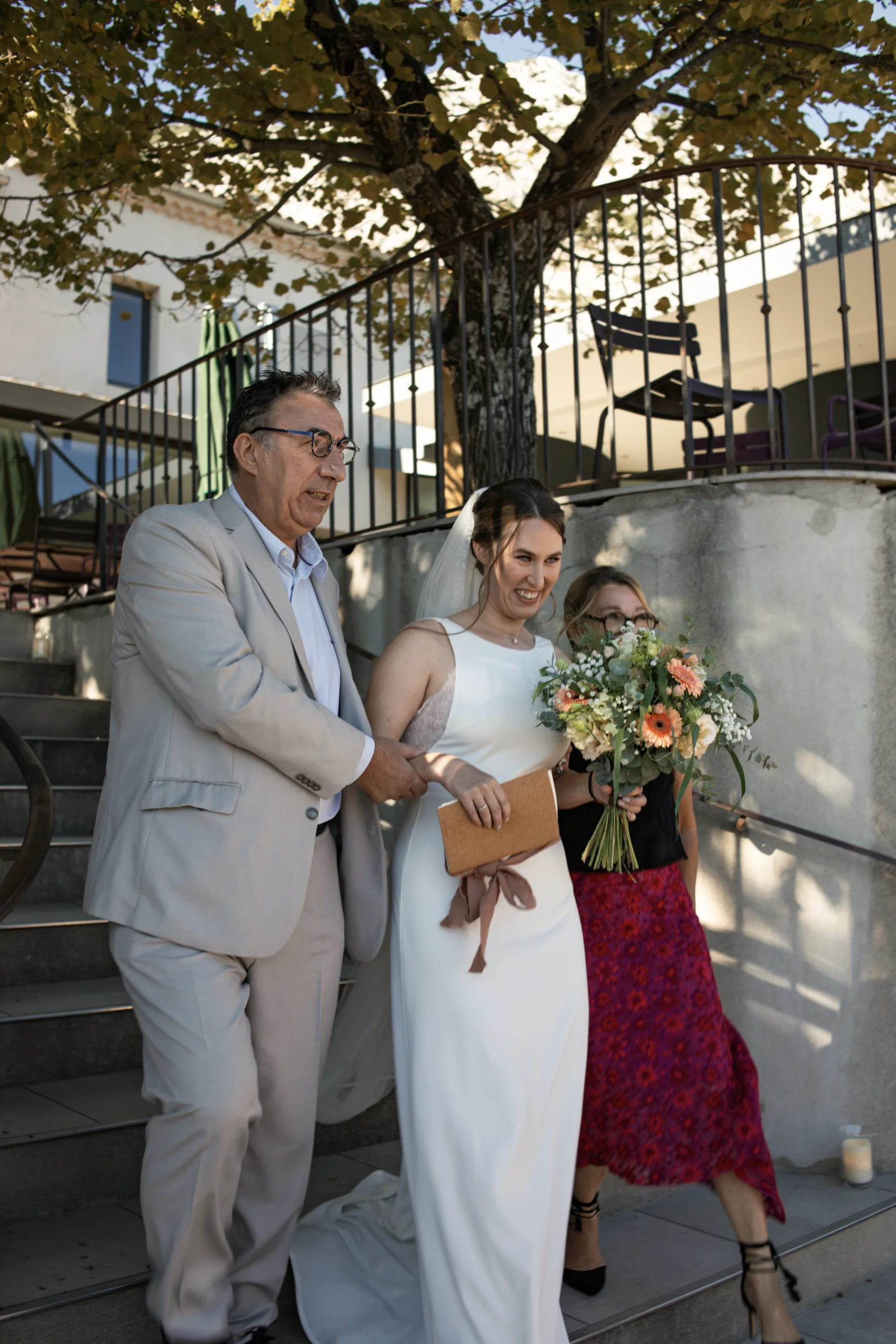 La mariée, aux bras de ses parents, se rend à sa cérémonie laique lors de son mariage en provence.