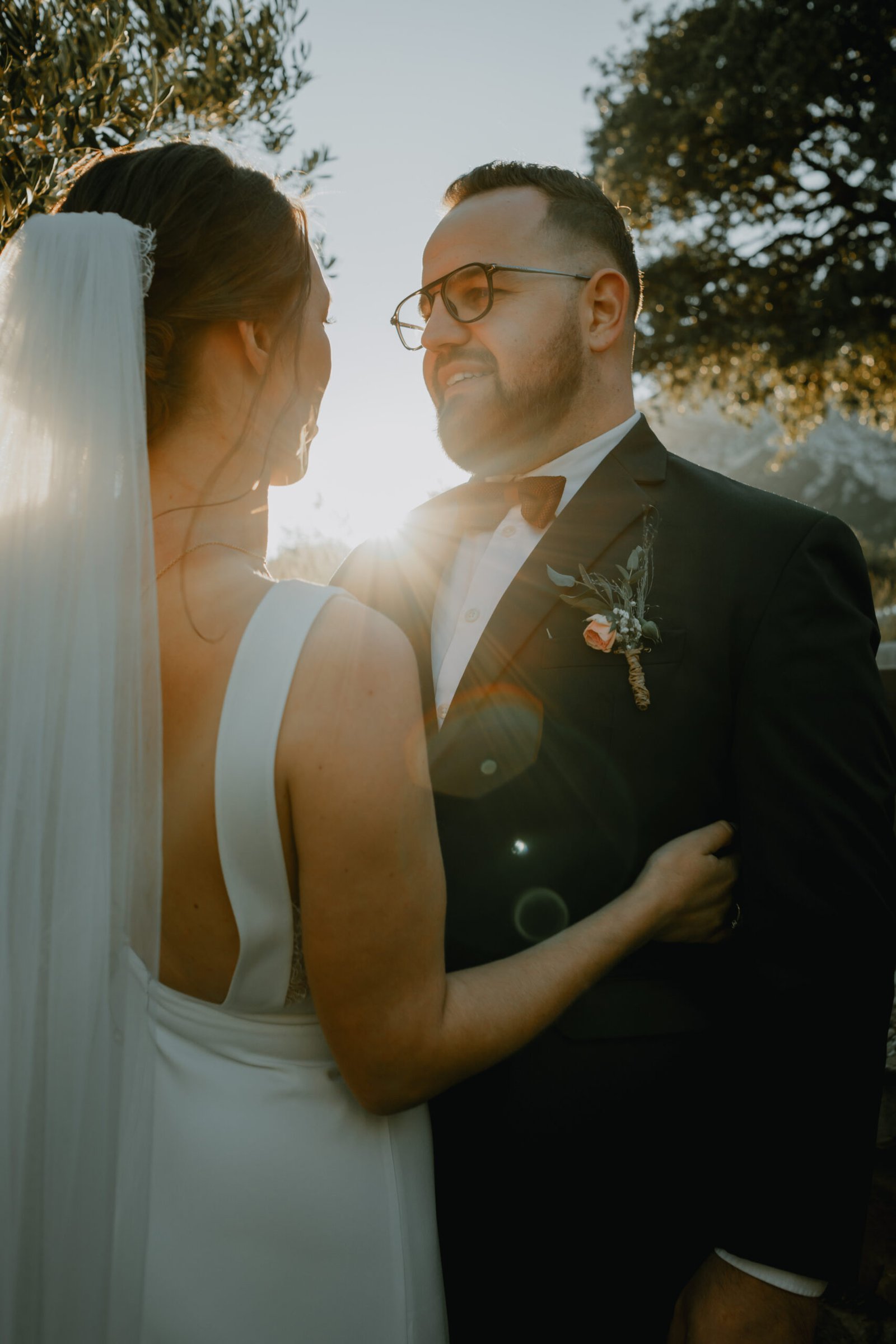 Un couple devant un beau coucher de soleil passant entre les branches d'oliver. Un mariage en provence au Relais de St Ser.