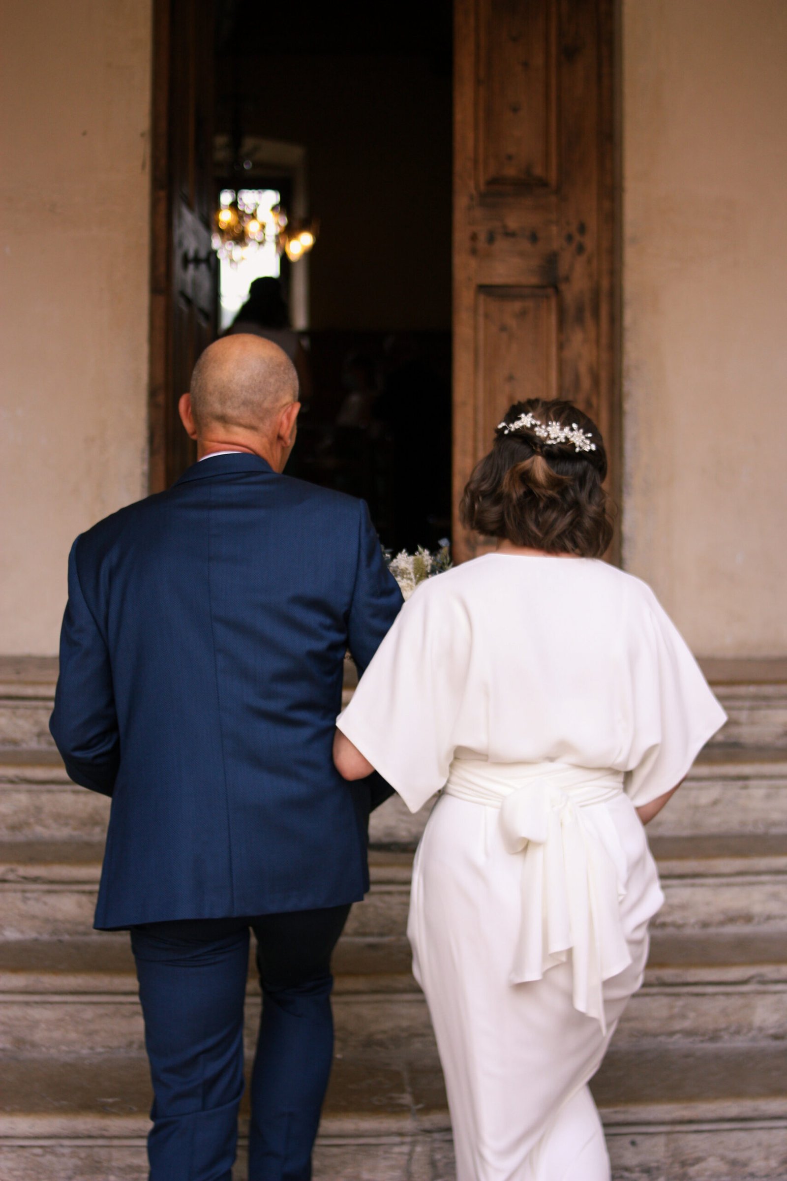Une mariée arrivant à la mairie au bras de son père, lors de son mariage civil en Provence.