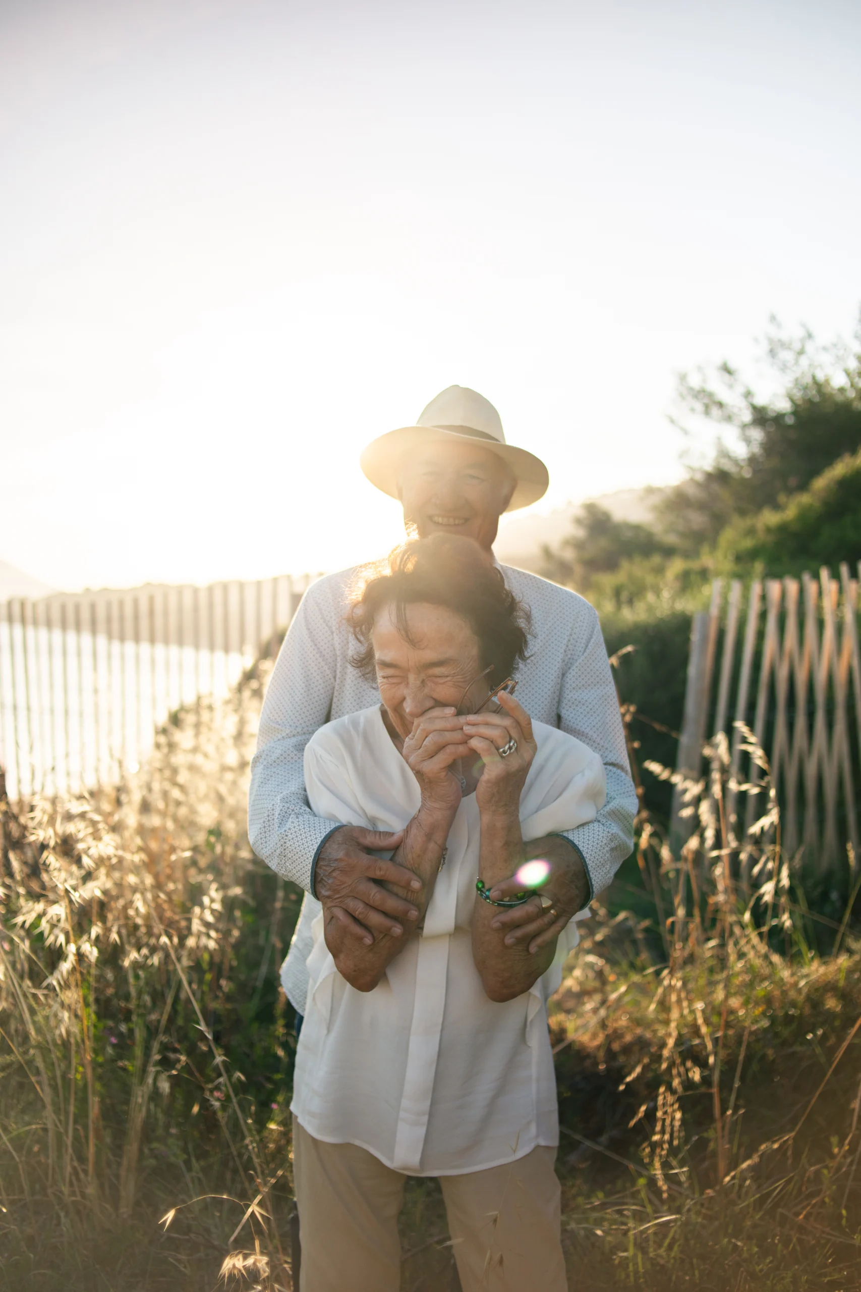 Un couple riant au coucher du soleil, lors d'une séance photo en bord de mer.