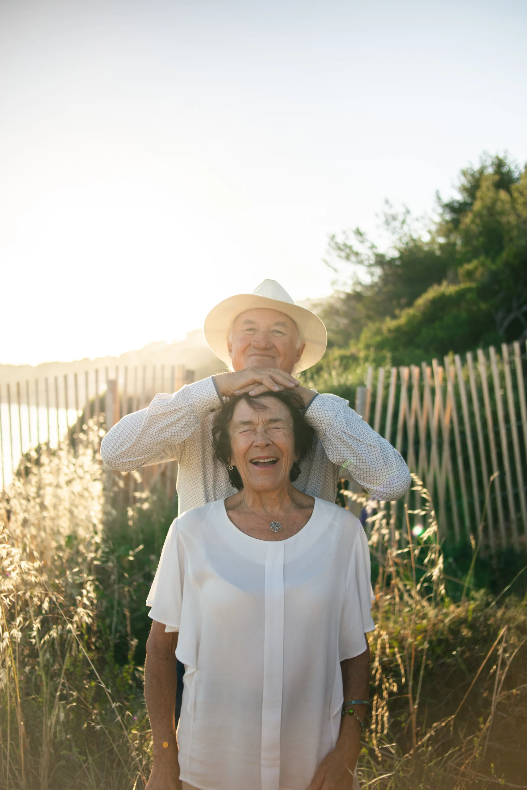 Une couple sénior, lors d'une séance photo de couple à Hyères, dans le Var. Ils rient aux éclats au coucher du soleil.