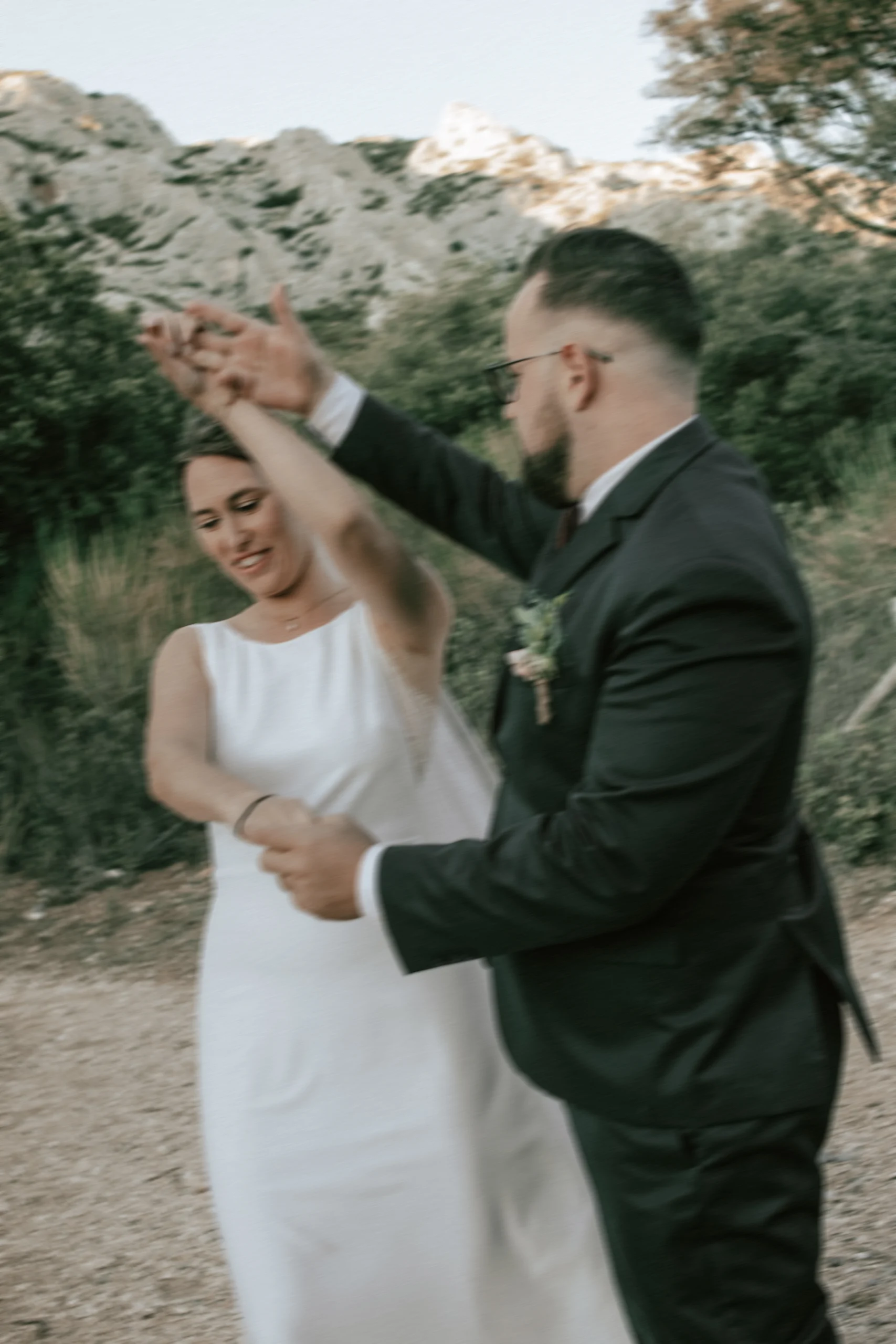 Deux jeunes mariés dansent devant la montagne Saint Victoire, au Relais de St Ser. Une photo prise par une photographe de mariage documentaire.