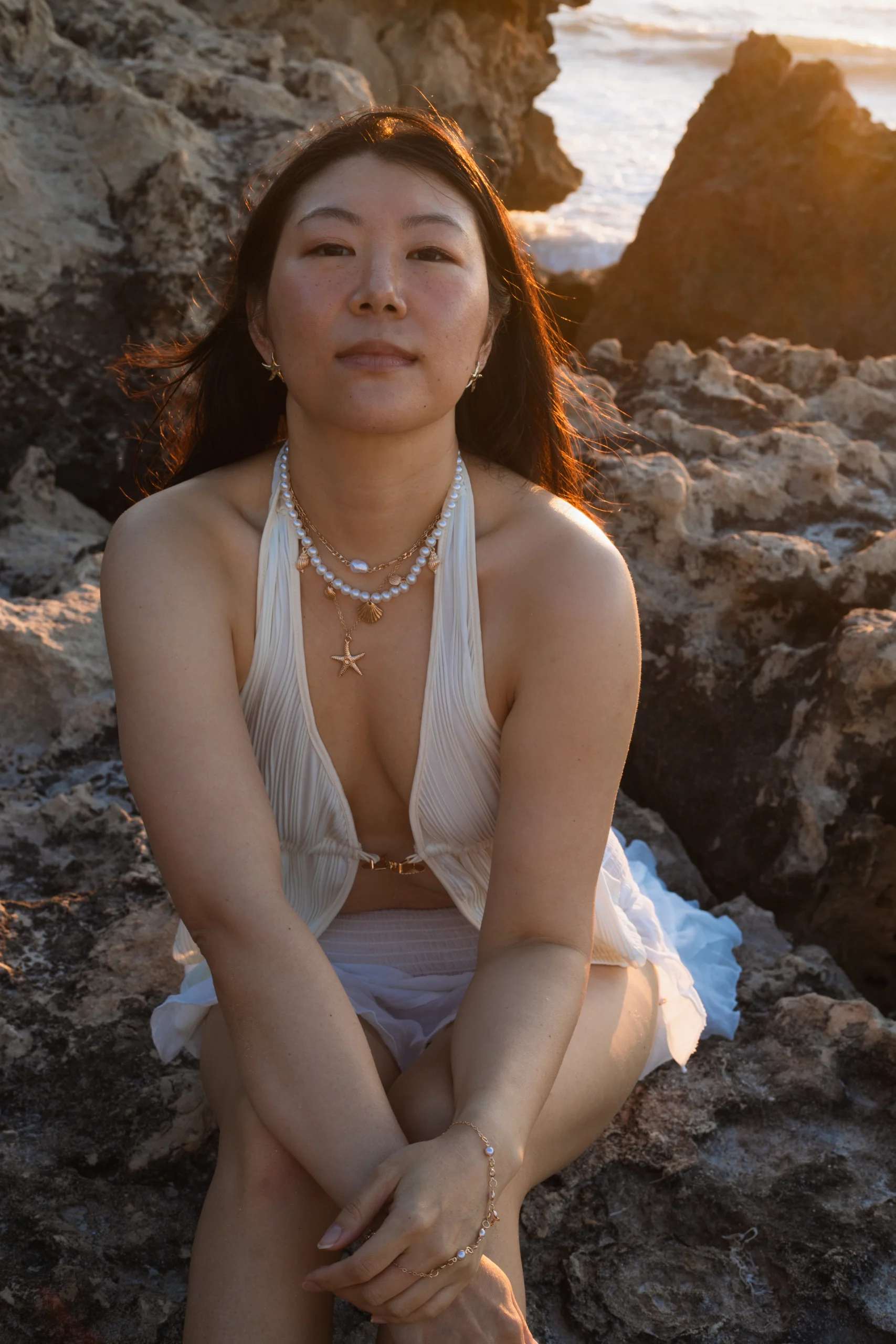 Photo d'une jeune femme assise sur un rocher, le regard confiant. Photo prise une photographe de portraits féminins dans le Var.