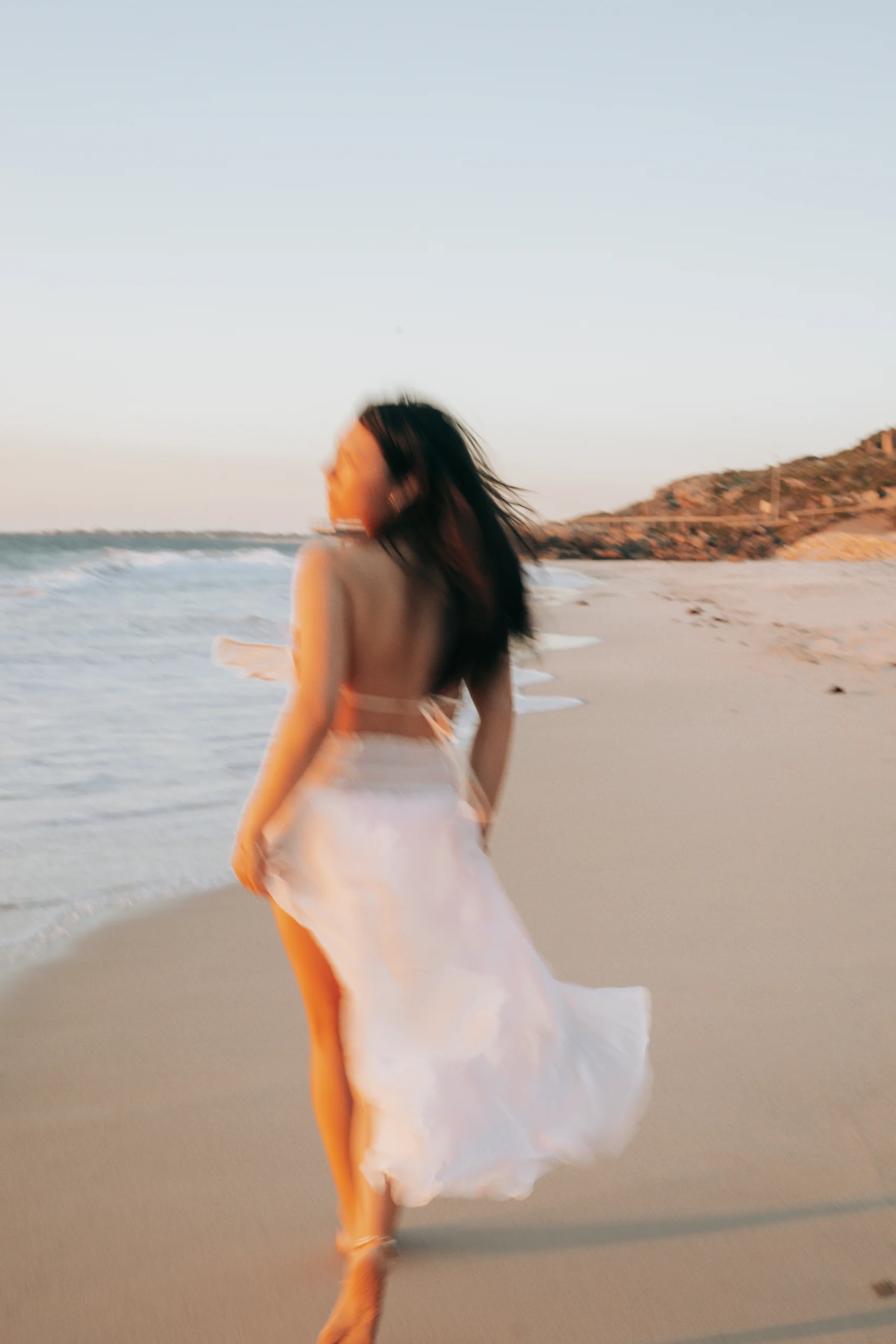 Une jeune femme, cours sur la plage dans une longue robe évasé. Photo prise lors d'un shooting photo dans le Var.