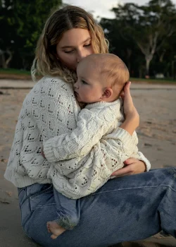 Une mère et son bébé, assis face au coucher du soleil, sur une plage du Var.