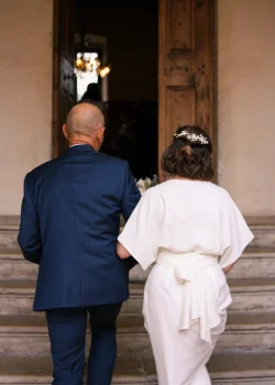 Une photographie de mariage documentaire qui capture la future mariée, au bras de son père, arrivant à la mairie.